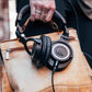 Audio-Technica ATH-M50xENSO headphones placed on a brown leather bag — showcasing durable metal frame, soft earpads, and wired connection perfect for studio and daily use.