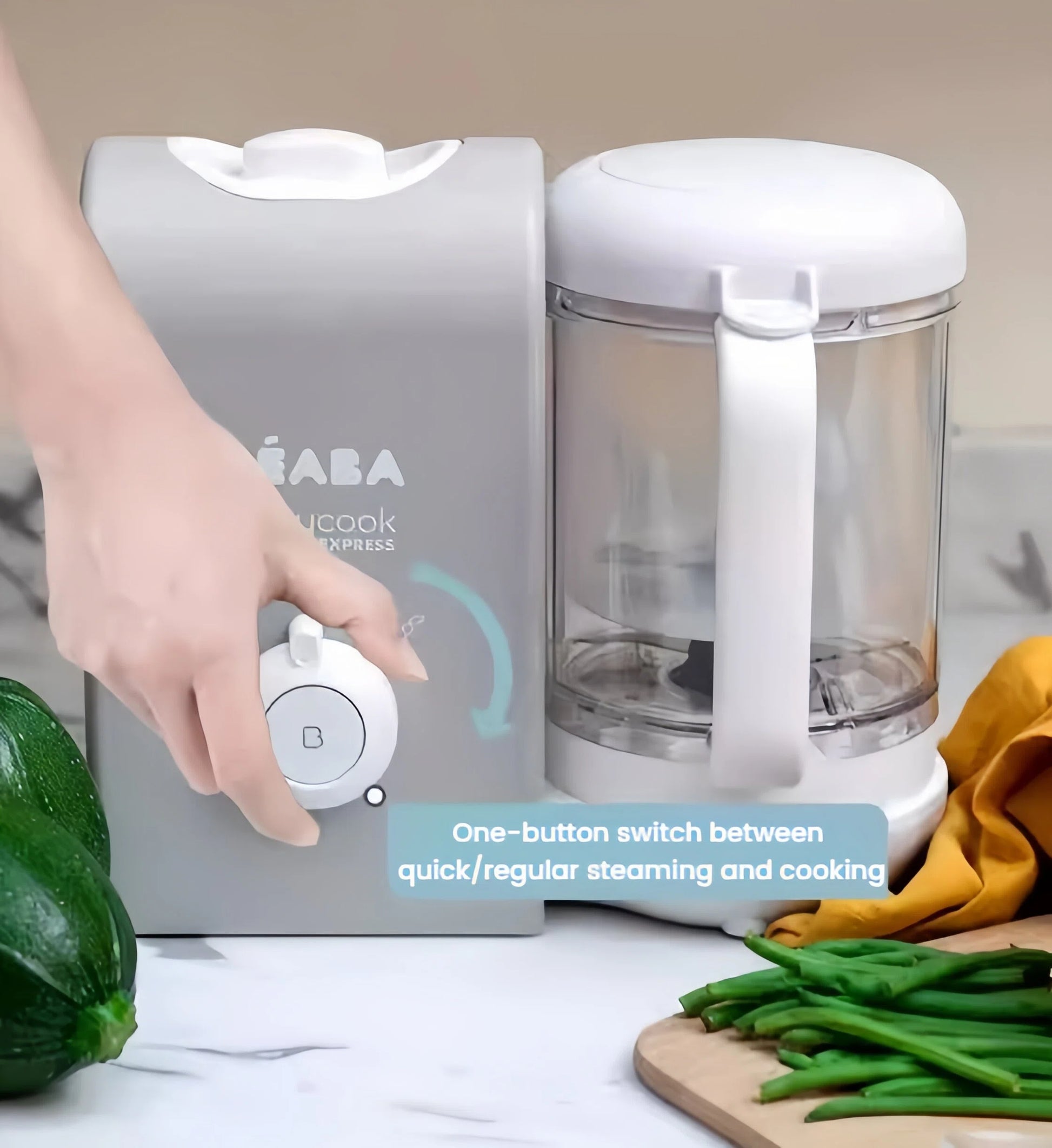Parent's hand turning the Beaba Babycook Express dial to switch between quick and regular steaming modes—intuitive one-button control for fast or gentle cooking.
