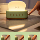 Green toaster night light glowing on dining table beside a vase, plate and softly blurred background