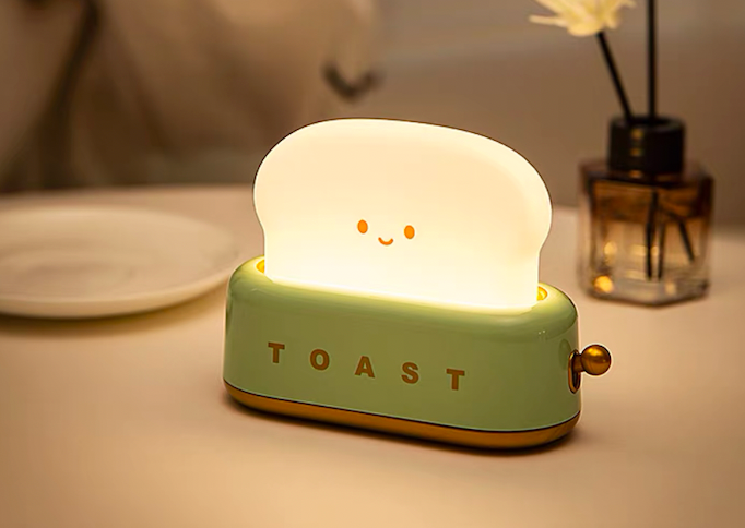 Finger pressing brass lever on green toaster night light with three step-by-step thumbnails showing the press-to-toggle action