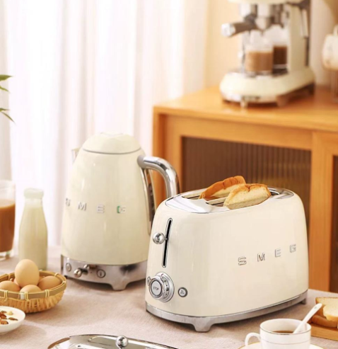 A beautiful lifestyle image showing the Smeg 4-Slice Toaster in cream as part of a matching breakfast set with the Smeg 50's Style Kettle, creating a coordinated retro kitchen aesthetic.